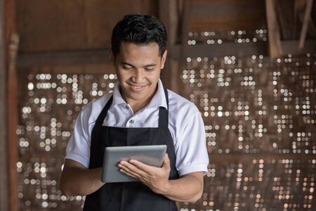 Portrait of male potter using digital tablet in pottery workshop. selling his product onlineの写真素材