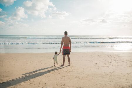 portrait of Daughter and father standing side by side on the beach. taken from behindの写真素材