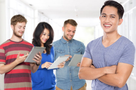 portrait of young asian male with his friend using tablet gadget at the background