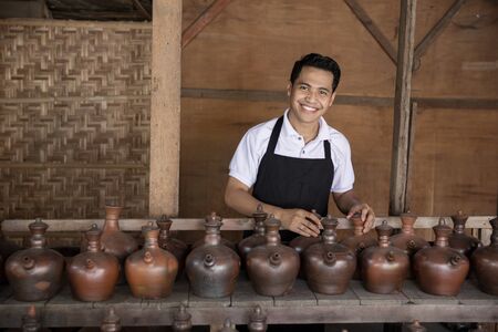 portrait of Smiling male potter holding his product in pottery workshopの写真素材