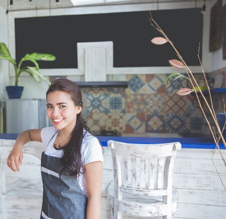 portrait of young asian pretty cafe worker smiling to cameraの写真素材