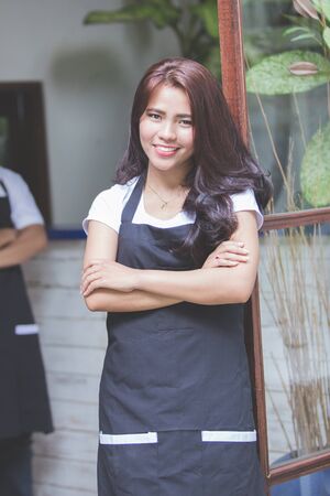 portrait of young asian pretty cafe worker smiling to cameraの写真素材