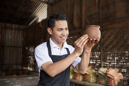 male potter checking vase in pottery workshopの写真素材
