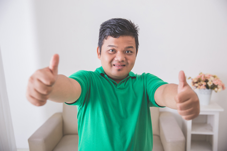 portrait of asian male smiling to camera and showing thumb upの写真素材