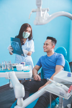 Doctor talking with her patient and teaching a radiograph. Dentist concept.