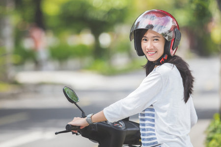 portrait of happy asian woman riding on motorbike in city street