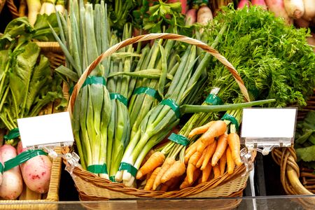 portrait of baby carrots and spring onions in basket at groceryの写真素材