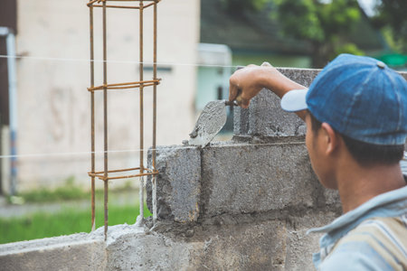 Close up of industrial bricklayer installing cement bricks on construction site