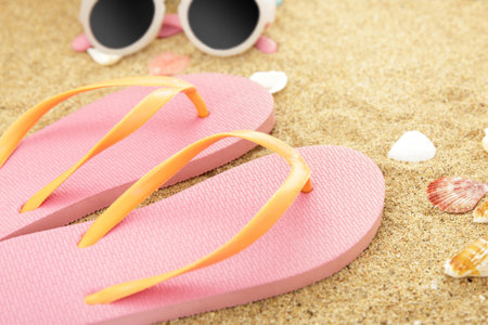 close up portrait of pink flipflops on beach sandsの写真素材