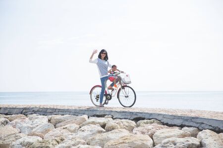 portrait of mother and baby riding on a bicycle in the beachの写真素材