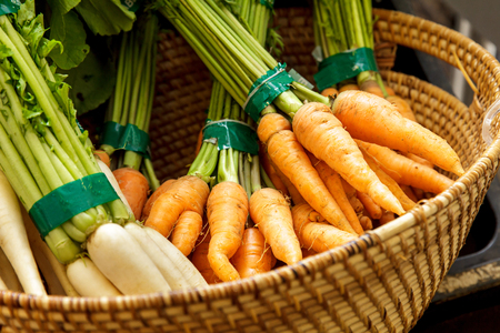 portrait of fresh carrot and radish in basket at groceryの写真素材