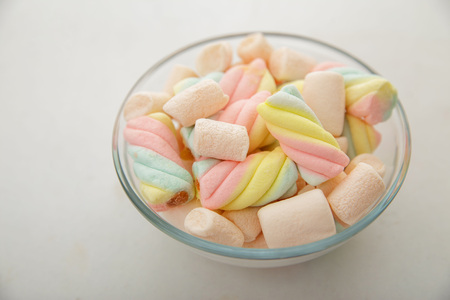 close up portrait of a bowl of sweet colorful marshmallow isolated on white backgroundの写真素材