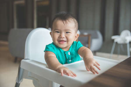 portrait of cute little girl sitting on a high chair. ready to have a mealの写真素材