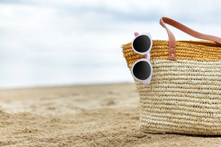 portrait of sunglasses and bag on sand for summer concept with copy spaceの写真素材