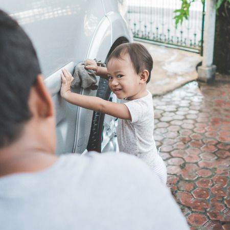 portrait of happy child being a little helper by helping her daddy cleaning up the carの写真素材
