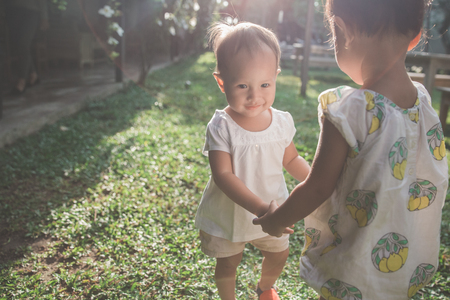 portrait of two little kid play together in park on summer dayの写真素材