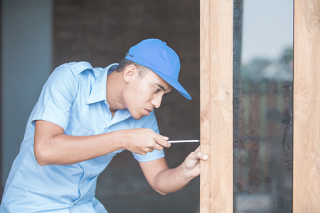 portrait of young asian worker installing doorsの写真素材