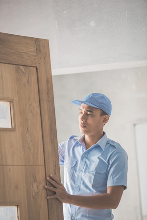 portrait of young asian worker installing doorsの写真素材