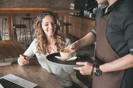 beautiful customer so happy getting her coffee served by the waitress at the cafeの写真素材