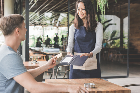 customer paying his bills using credit card, assisted by waitressの写真素材