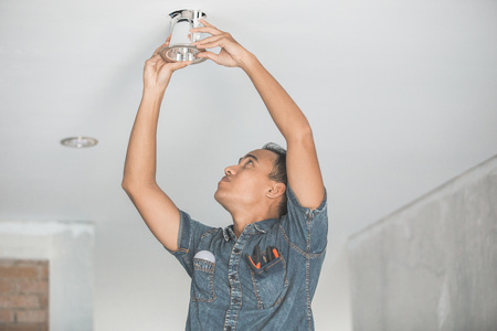 portrait of asian Electrician fitting a ceiling lightの写真素材