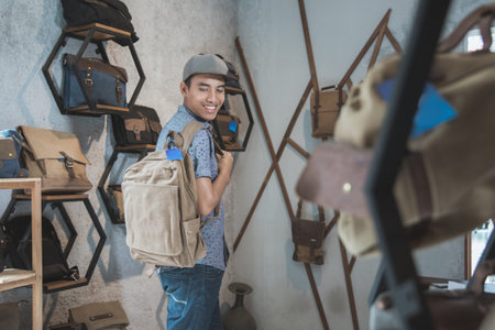 asian man trying to put on a bag at a male bag shopの写真素材
