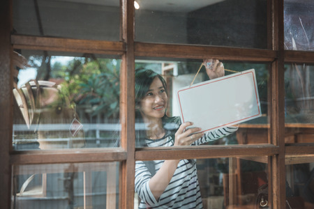 attractive asian business woman turning the open sign of her shopの写真素材