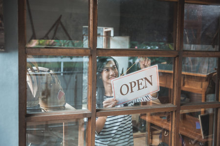 attractive asian business woman turning the open sign of her shopの写真素材