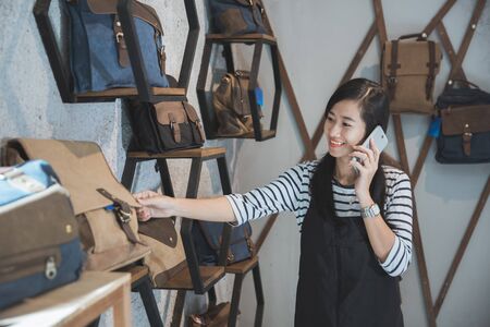 young asian business owner talking to mobile phone in her fashion storeの写真素材