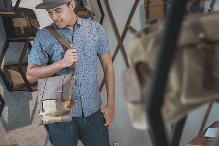 asian man trying to put on a bag at a male bag shopの写真素材