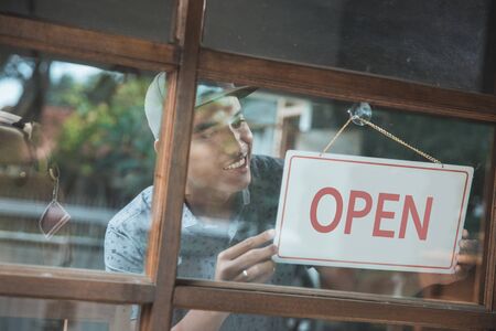 business owner turning the open sign of his shopの写真素材