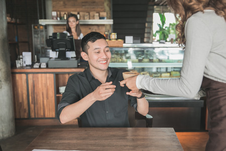 portrait of a female waitress serving coffee to a male customerの写真素材