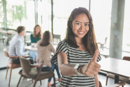 portrait of young asian woman showing thumb up after meeting with her teamwork