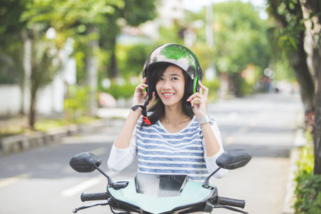 happy asian woman put helmet on before riding a motorbikeの写真素材