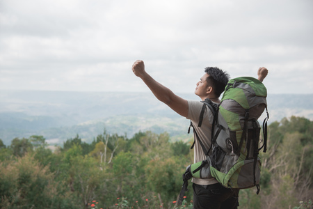 Hiker - man hiking in nature raise his arm, once he reach the topの写真素材