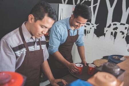 portraif of two small cafe owner busy working in their coffee shopの写真素材