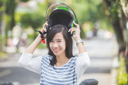 happy asian woman put helmet on before riding a motorbikeの写真素材