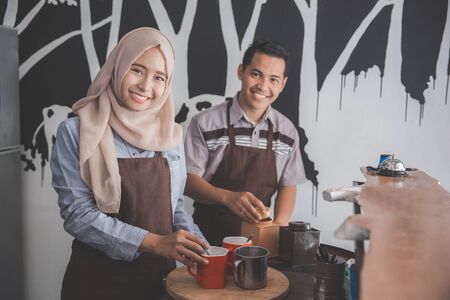 portraif of two male and female cafe owner busy working in their coffee shopの写真素材