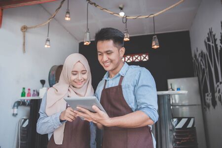 two business partner using tablet in front of their coffee shop. muslim entrepreneur conceptの写真素材