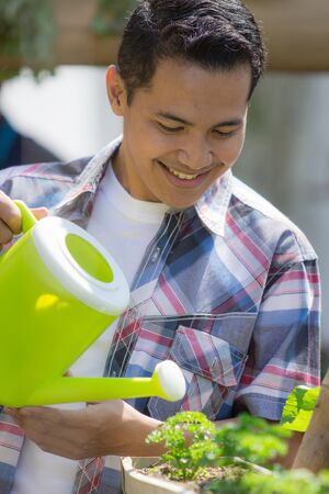 portrait of happy young man watering his gardenの写真素材