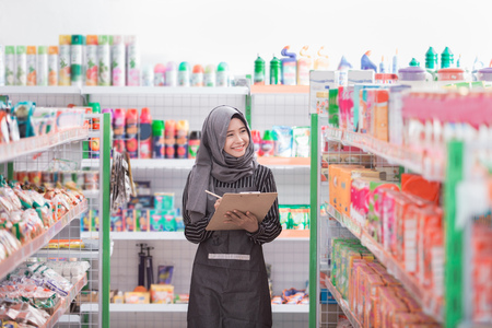 asian female muslim shopkeeper check the product at supermarketの写真素材