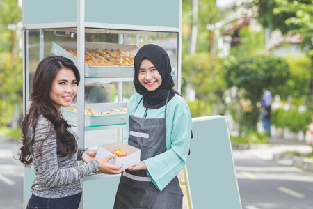 woman buying fresh cake at halal food stall. street food conceptの写真素材