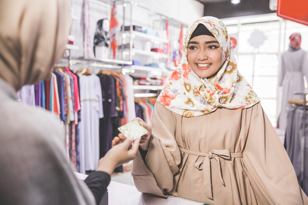 asian muslim woman paying with credit card in a fashion boutiqueの写真素材