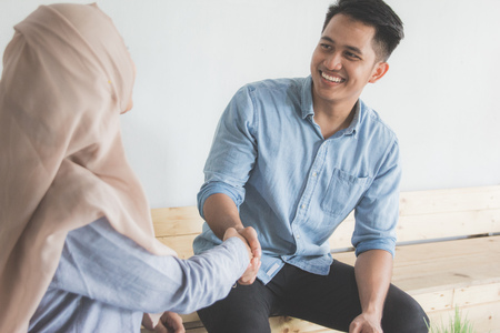 two female and male business partner shaking hand during casual meeting in cafeの写真素材
