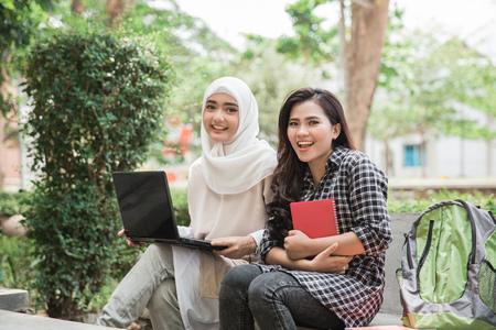 portrait of two attractive asian college student using laptop on campusの写真素材