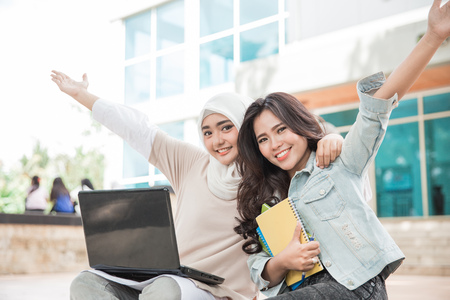portrait of two attractive asian college student using laptop on campusの写真素材