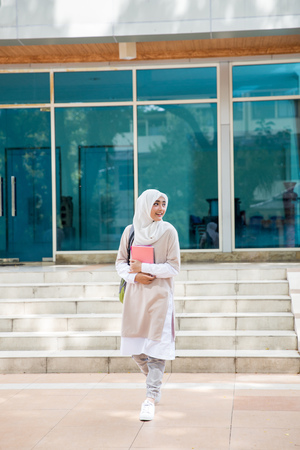 cheerful asian female university students wearing head scarf walking on campusの写真素材