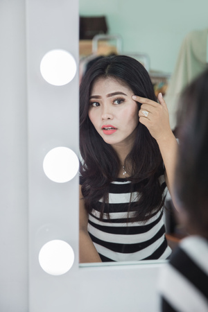 woman looking at her skin problem in the mirrorの写真素材