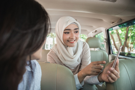 portrait of asian woman showing direction to the driver using GPS in her mobile phoneの写真素材