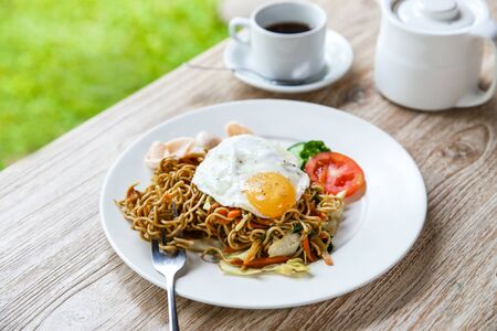 portrait of homemade indonesian fried noodle with a cup of hot tea for breakfastの写真素材